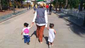 Dos menores extranjeros caminan de la mano de un agente de Save the Children España