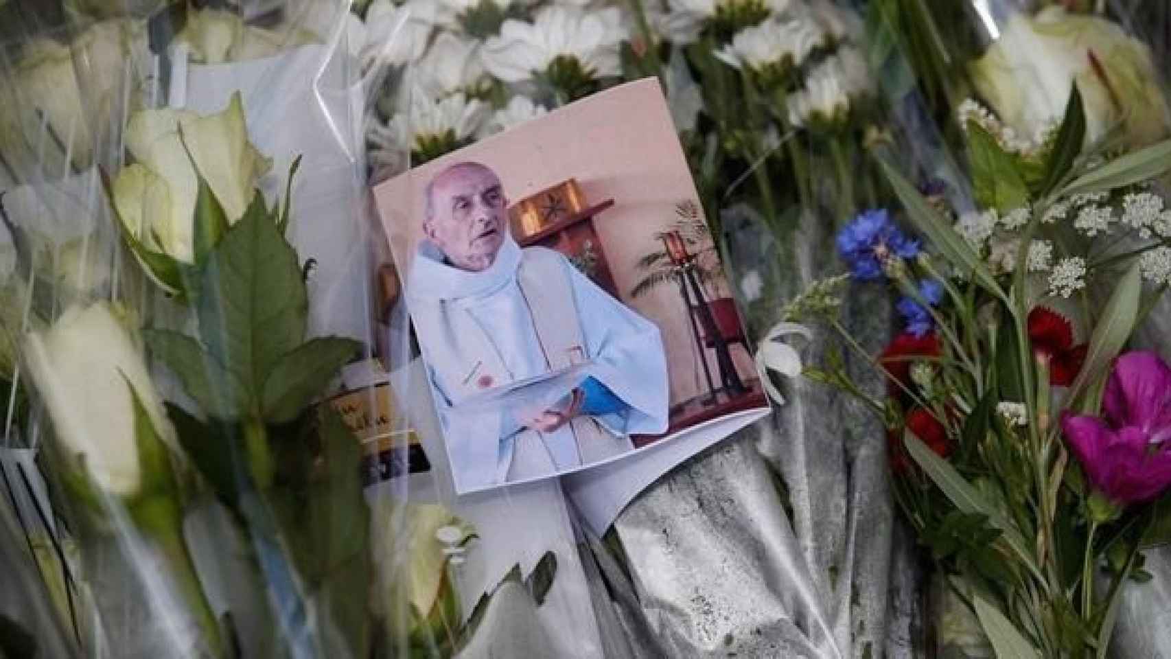 Una fotografía del sacerdote asesinado Jacques Hamel se observa entre las flores depositadas en un altar improvisado en Francia.
