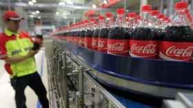 Un trabajador en una fábrica de Coca Cola junto a unas botellas, en una imagen de archivo.