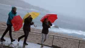Mujeres se protegen del temporal en A Coruña / EFE
