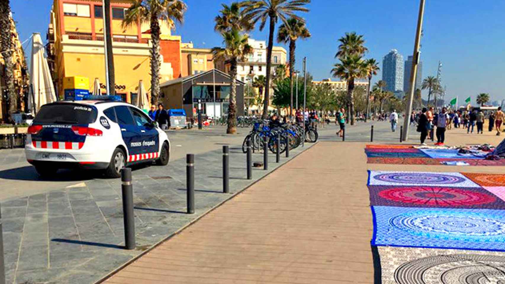 Una patrulla de Mossos d'Esquadra, frente a un grupo de 'manteros' en la playa de Barcelona / CG