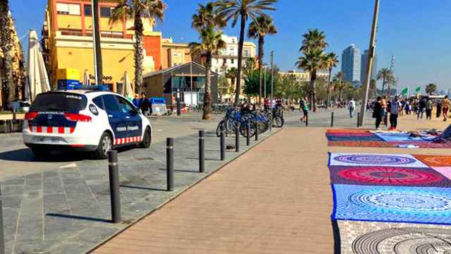Una patrulla de Mossos d'Esquadra, frente a un grupo de 'manteros' en la playa de Barcelona / CG