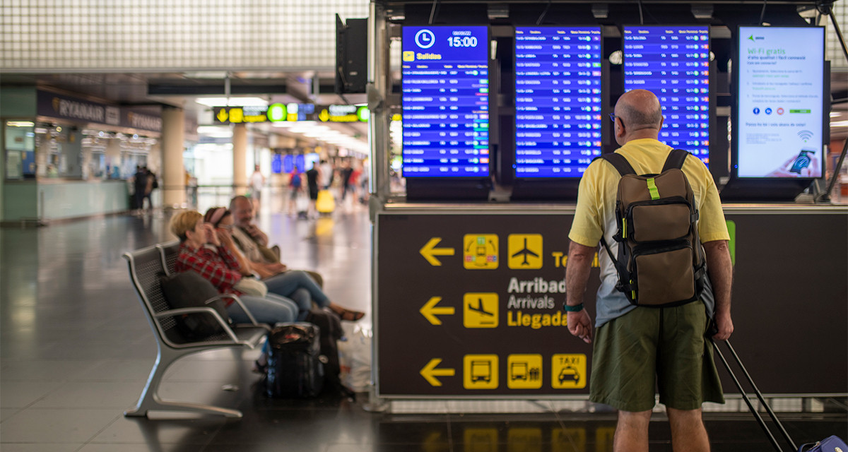 Un hombre mira un panel de llegadas y salidas en el aeropuerto de El Prat, que sufre la huelga aérea de Francia / EUROPA PRESS