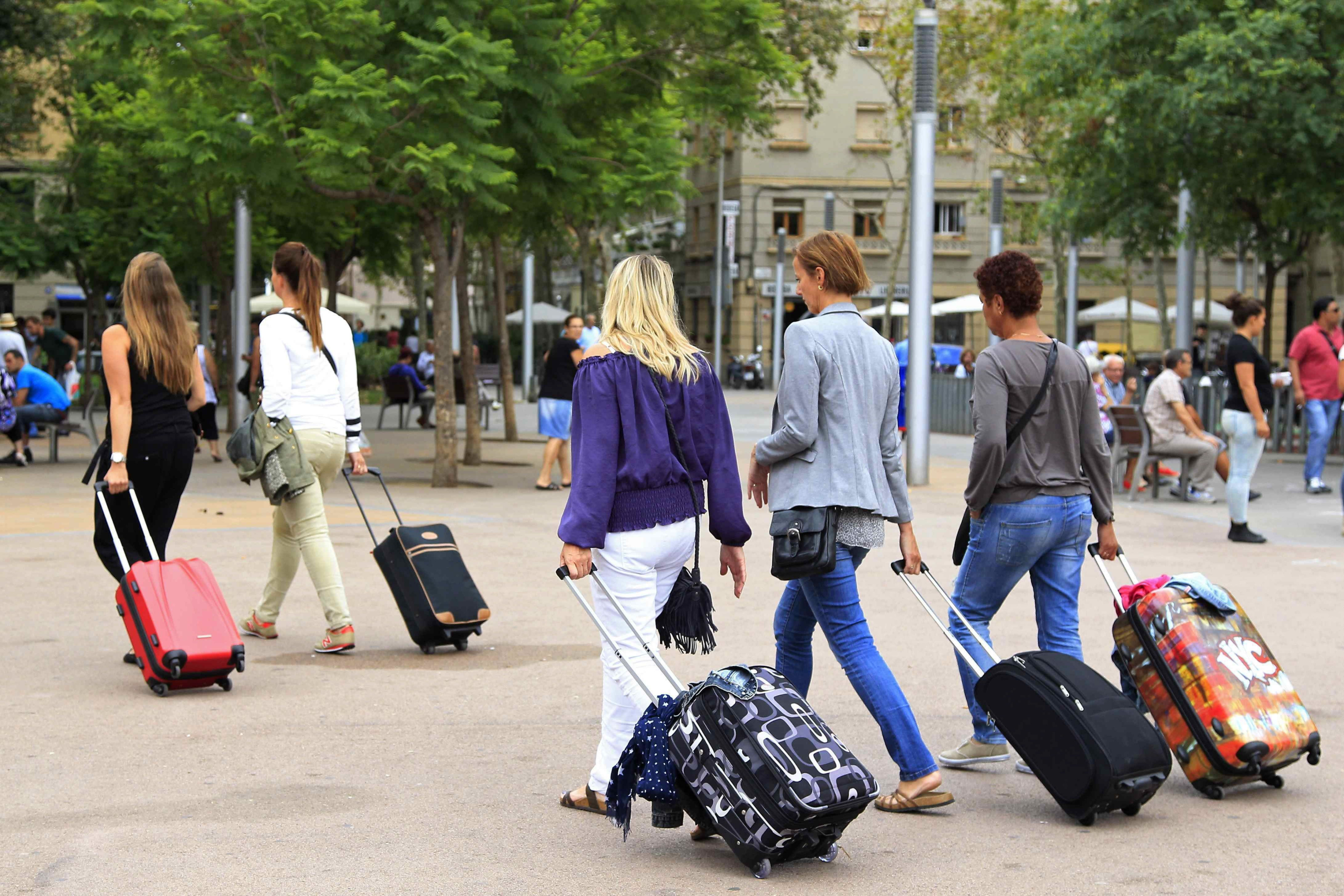 Varias turistas con maletas se dirigen a un hotel en una plaza de Barcelona / EFE