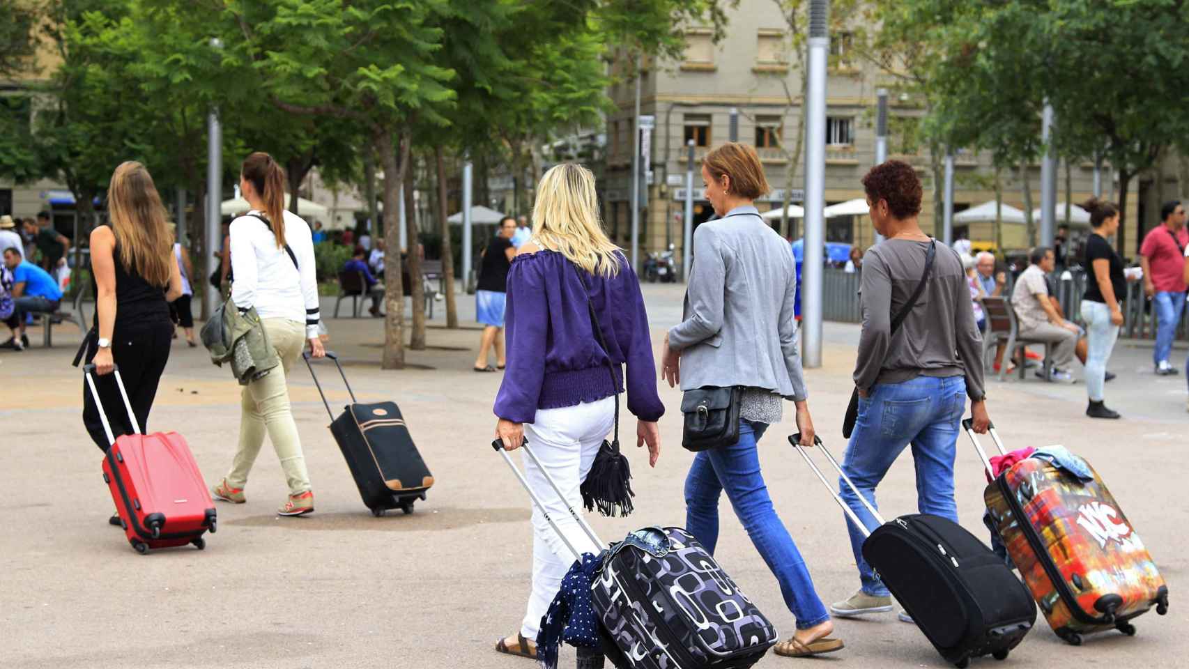 Varias turistas con maletas se dirigen a un hotel en una plaza de Barcelona / EFE