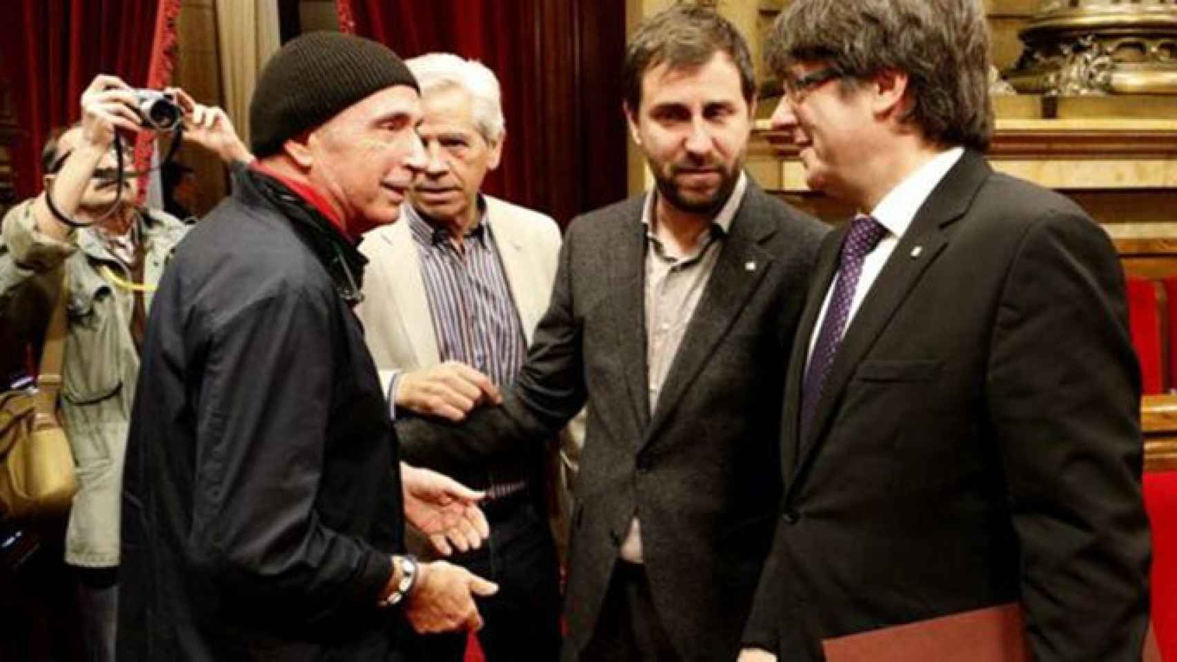 El diputado de JxS Lluís Llach saluda al presidente Carles Puigdemont en el Parlament / EFE