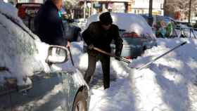 Dos personas quitan nieve de sus coches durante el temporal / EFE