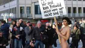 La artista sueca Milo Moire se manifiesta en la plaza Central de Colonia mientras sostiene un cartel: ¡Respétanos! ¡No somos carne de presa ni aunque estemos desnudas!