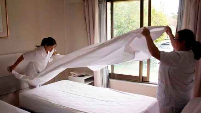 Dos camareras de piso arreglando una habitación de hotel / CG
