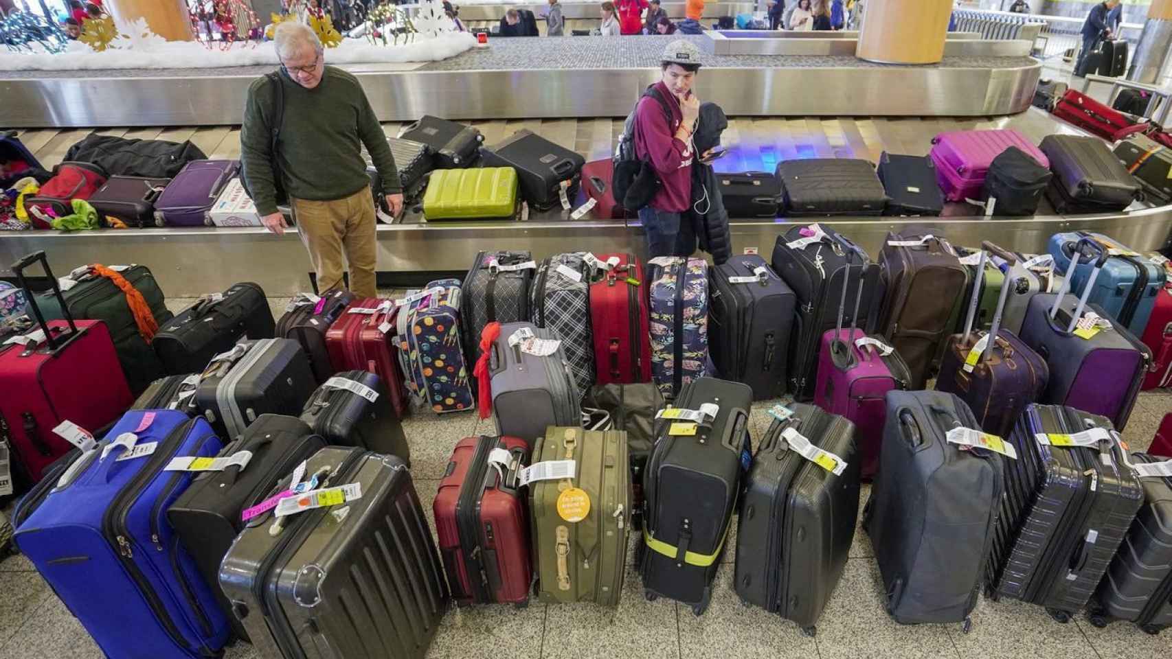 Un hombre busca su maleta entre muchas piezas de equipaje en un aeropuerto / EFE