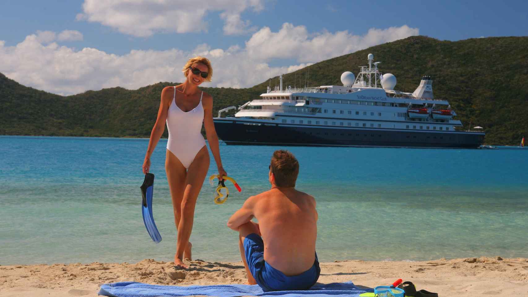 Una pareja de enamorados en la playa con un crucero detrás / AQUOTIC