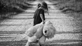 Una niña pasea por un camino arrastrando su peluche / CG