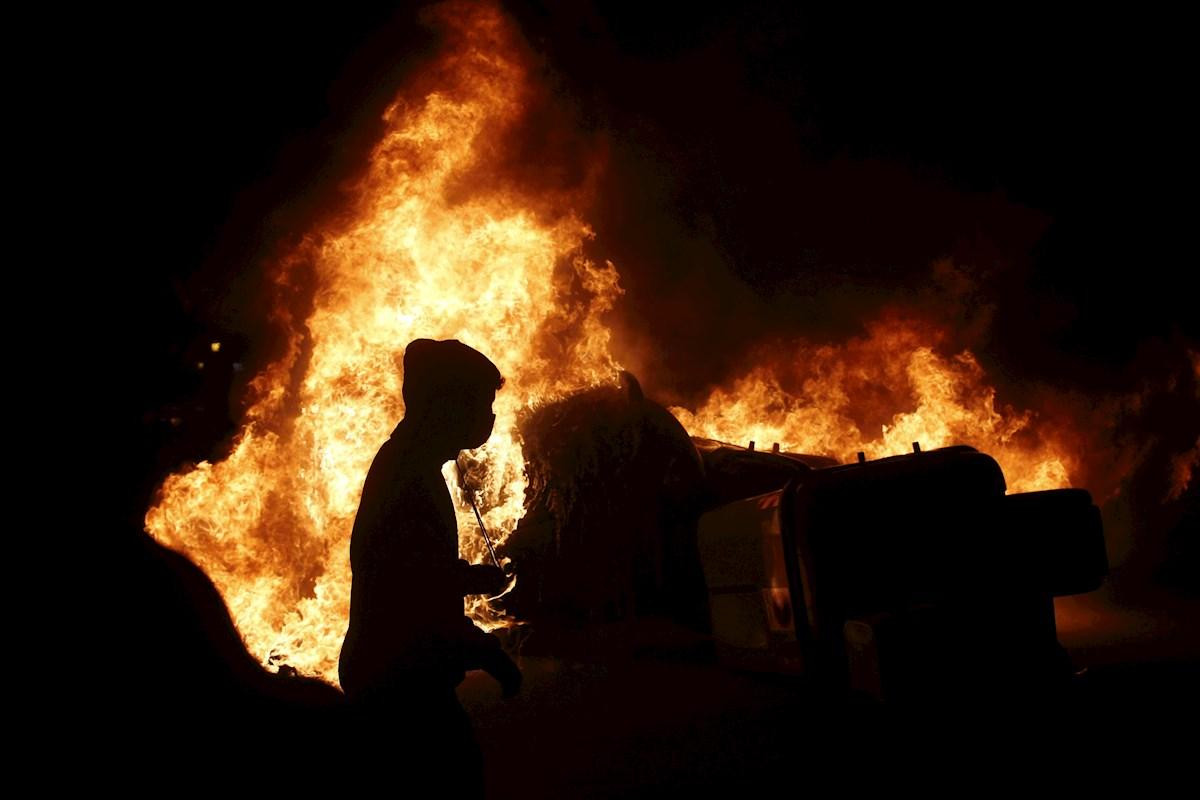 Un manifestante camina al lado de una barricada en llamas, en una nueva jornada de disturbios / EFE