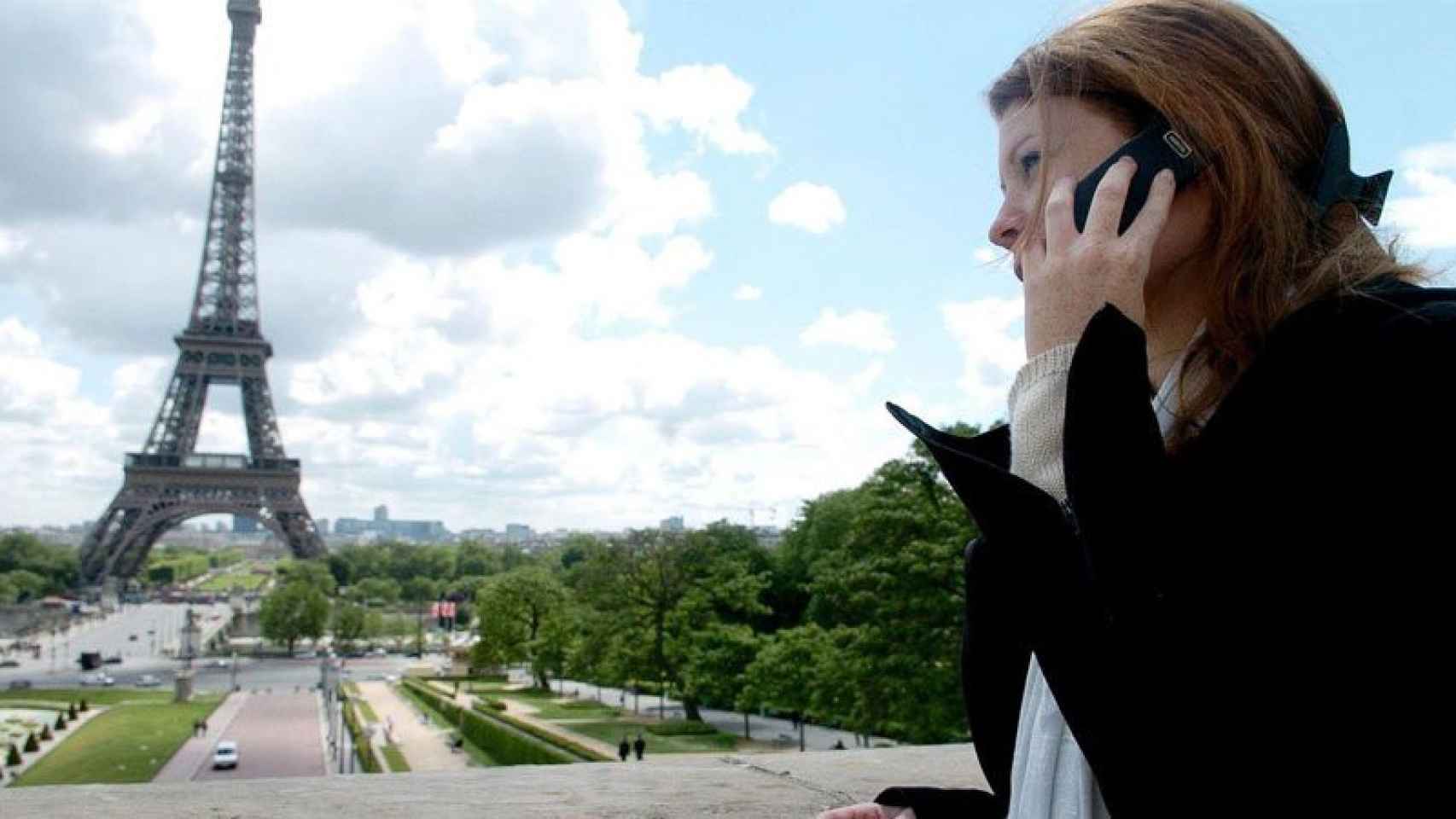 Una chica llama por teléfono al lado de la Torre Eiffel / CG