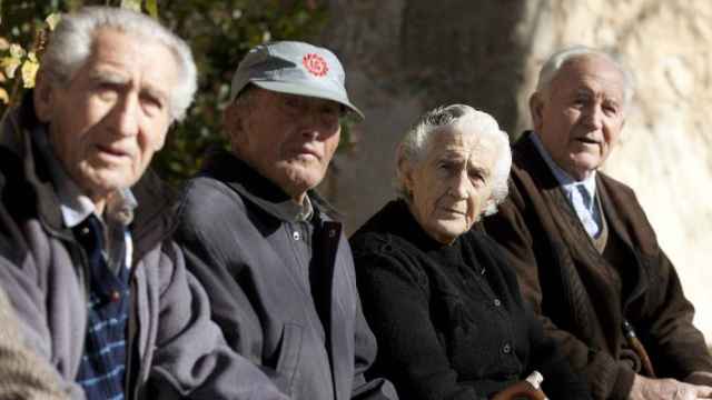 Cuatro jubilados sentados en un banco que cobran pensión