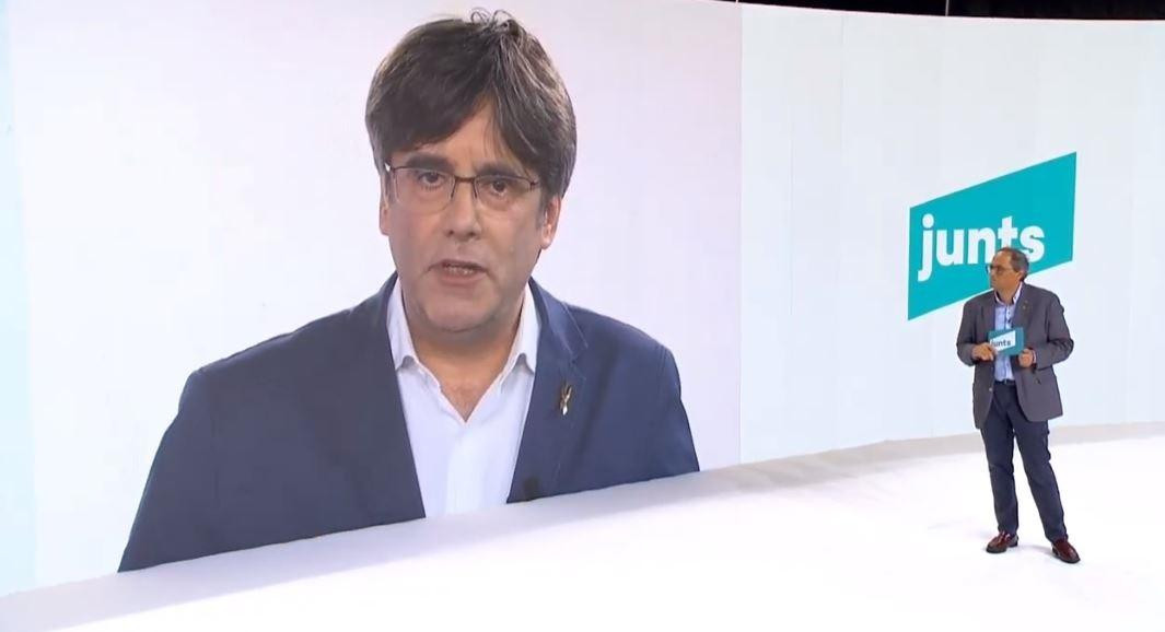 Carles Puigdemont, en pantalla, con el presidente Quim Torra, en el acto de JxCat / EP