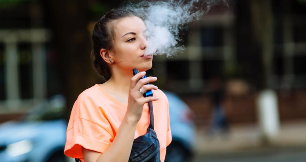 Una joven vapea un cigarrillo electrónico