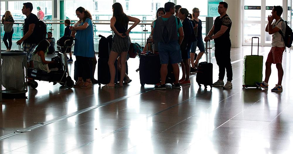 Varias personas esperan frente los mostradores de la aerolínea Vueling en el aeropuerto del Prat, Barcelona / EFE
