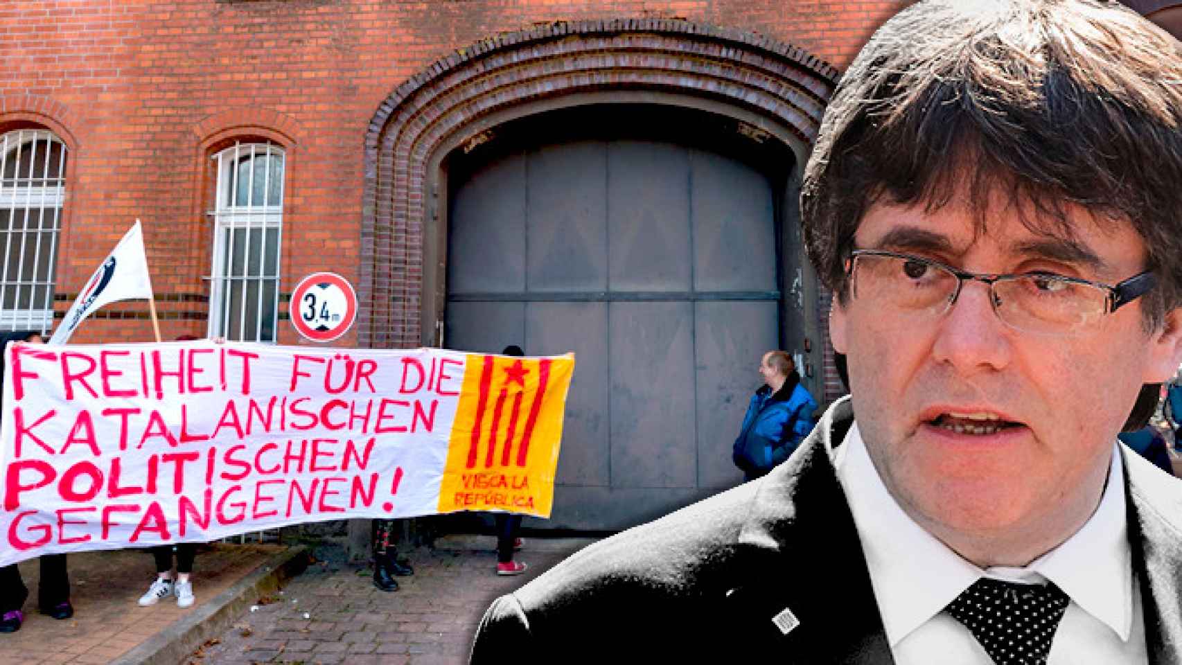 Puigdemont ante la cárcel de Neumünster donde varias personas sostienen una pancarta en la que se lee en alemán Libertad para los presos políticos catalanes