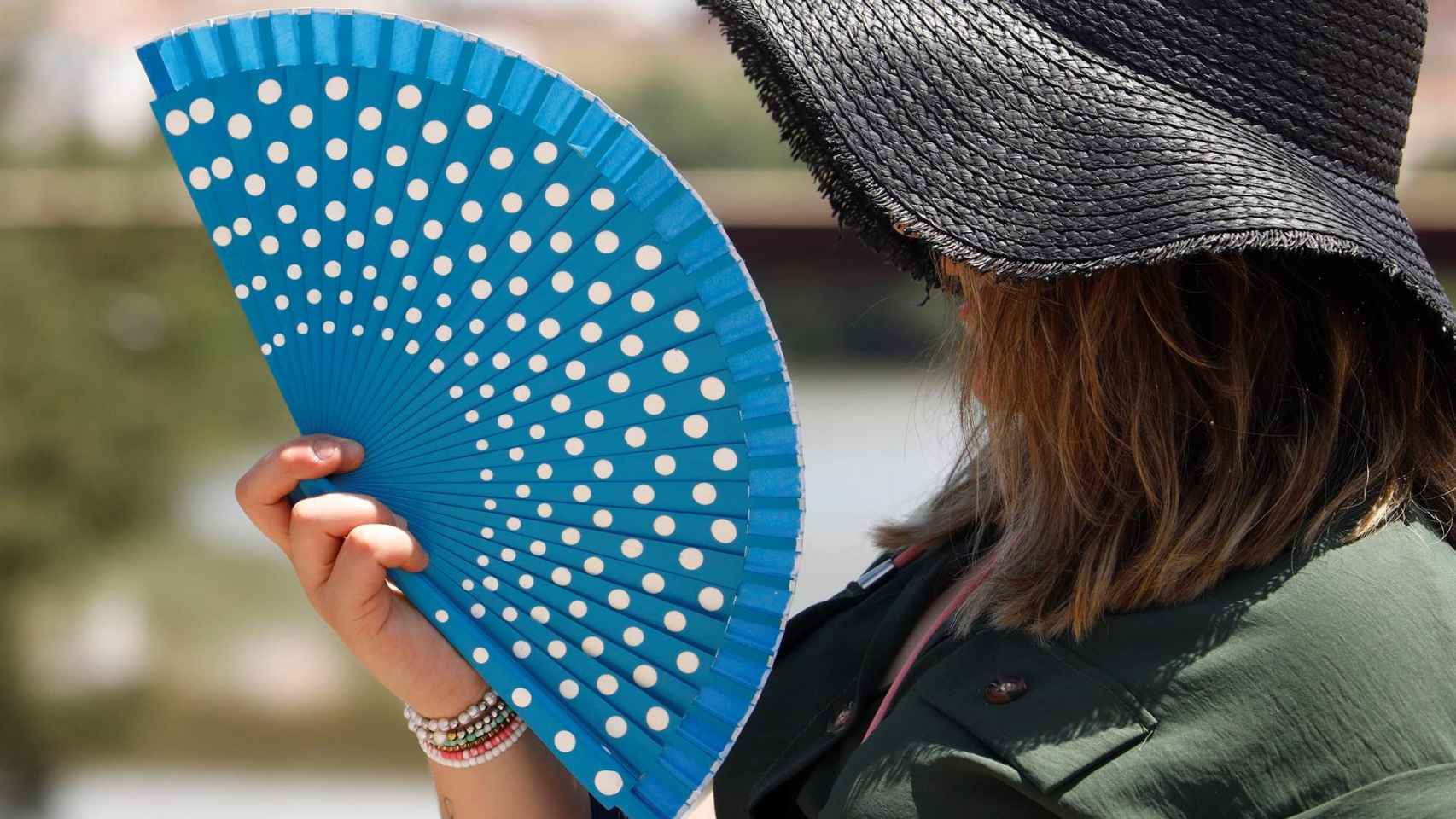Una mujer se protege de las altas temperaturas con un sombrero y un abanico en Córdoba, tras la llegada de la ola de calor del norte de África / EFE - Salas