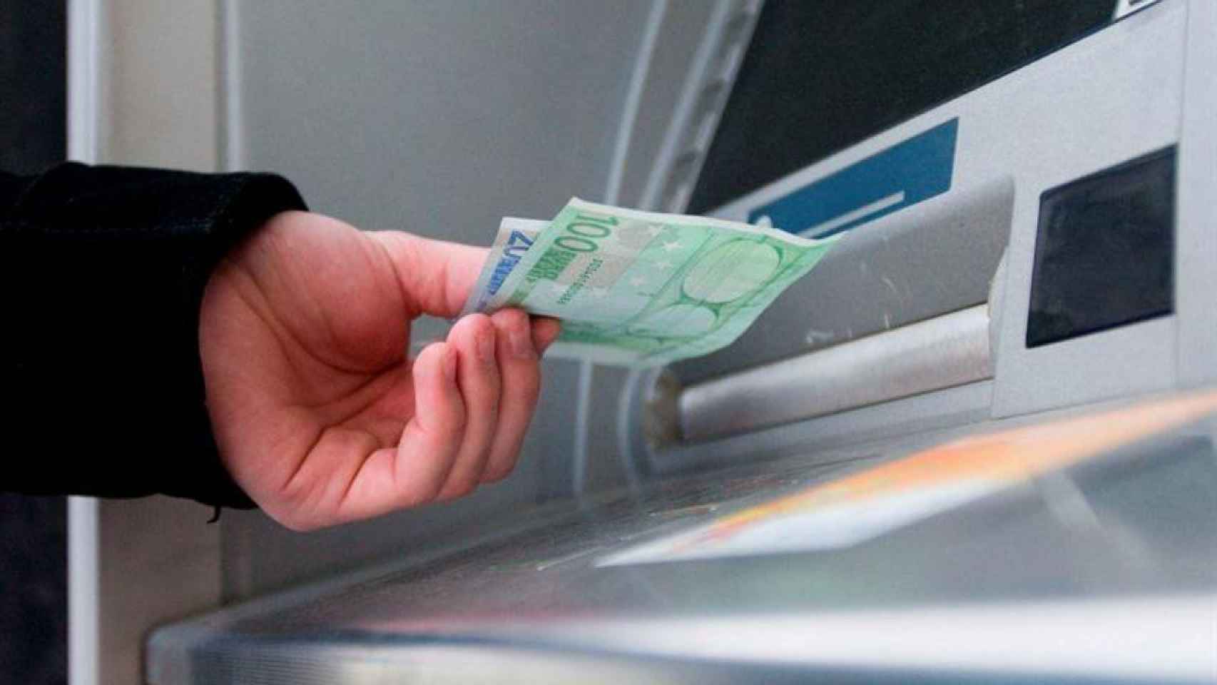 Una persona sacando dinero de un cajero automático, en una imagen de archivo / EFE