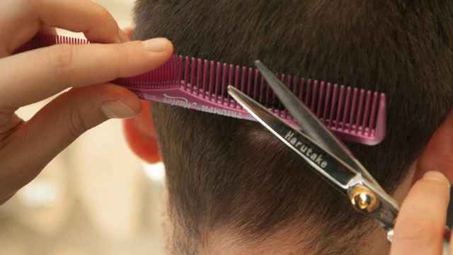 Un peluquero rapa la cabeza de una mujer en su barbería / CG