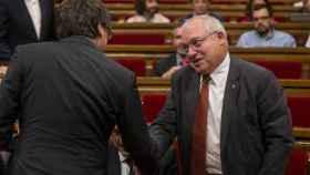 El exconsller de Cultura, Lluís Puig, saluda al expresidente de la Generalitat, Carles Puigdemont, en un pleno del Parlament / EFE