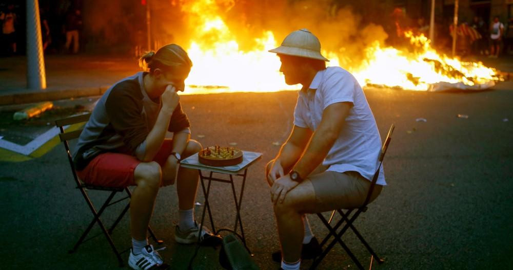 Dos jóvenes juegan al ajedrez ante una barricada en llamas durante los disturbios del independentismo violento en Barcelona / EFE