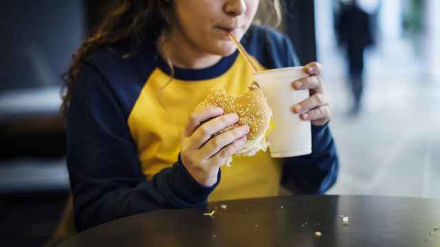Niña alimentándose de comida basura, una de las causas del sobrepeso