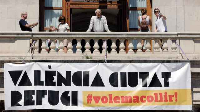 Joan Ribó (c) se asoma al balcón del consistorio de donde cuelga una pancarta de solidaridad con los viajeros del 'Aquarius' / EFE