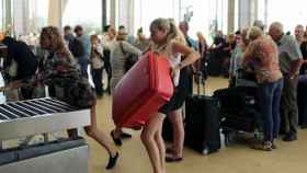 Una turista rusa carga una maleta sobre la cinta portaequipajes en un aeropuerto egipcio.