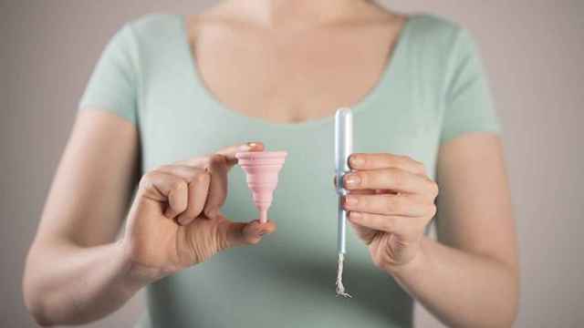 Mujer sosteniendo una copa menstrual y un tampón, métodos utilizados para la regla / PIXABAY