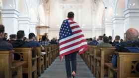 Un defensor de la comunidad de lesbianas, gais, bisexuales y transexuales (LGBT) porta una bandera estadounidense durante una vigilia por las 49 víctimas mortales, celebrada en una iglesia de Zúrich, Suiza.