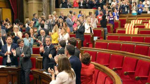 El presidente de la Generalitat, Carles Puigdemont, aplaude junto a los miembros del Govern la aprobación de la ley del referéndum, con los escaños de PSC, PP y C,s vacíos / EFE