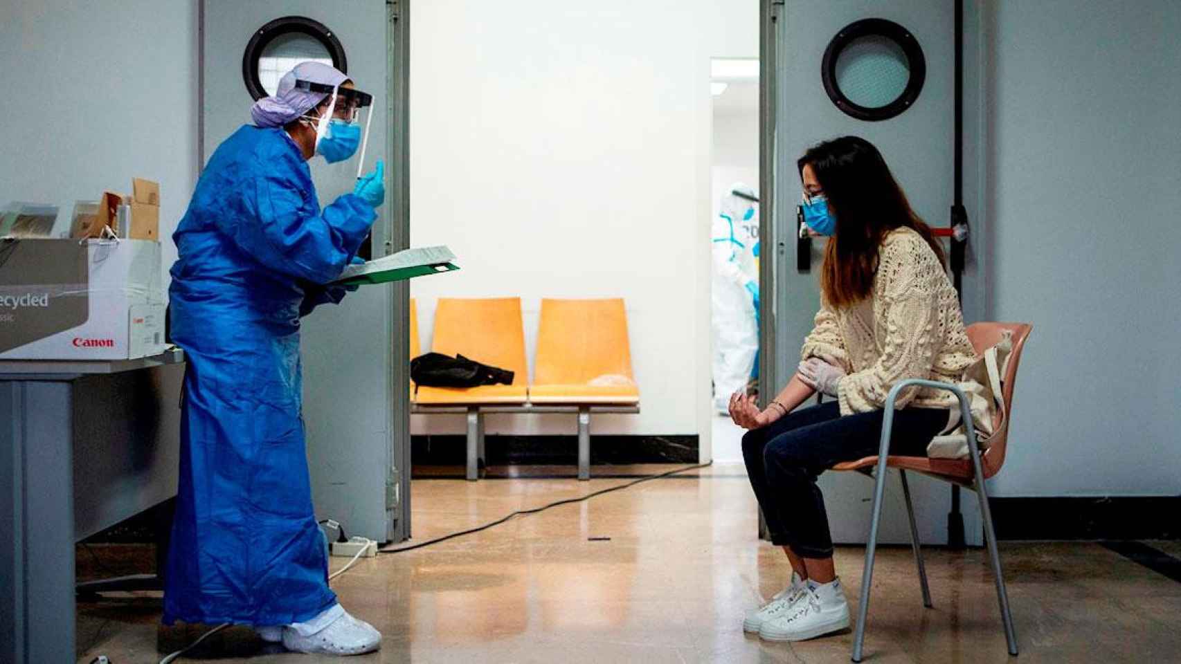 Una sanitaria protegida contra el virus atiende a una paciente en un ambulatorio catalán / EFE