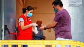 Imagen de una voluntaria de Cruz Roja lavando las manos con desinfectante a un ciudadano / EFE