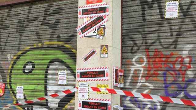 Carteles con el mensaje 'Perill, amiant en comú' y 'Amianto mata' en la sede de Barcelona en Comú / CG