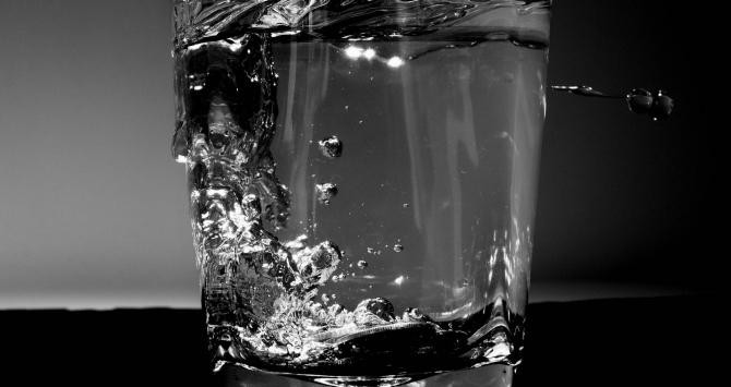 Vaso de agua frente un fondo oscuro / CG