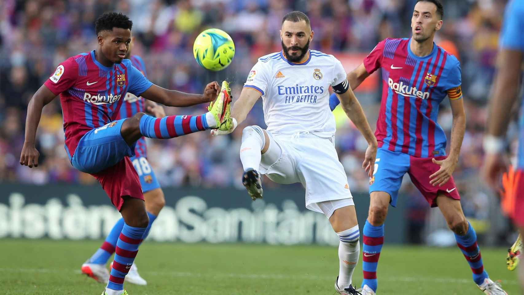 Benzema disputa un balón en el clásio entre Ansu Fati y Busquets, dos canteranos del Barça / EFE