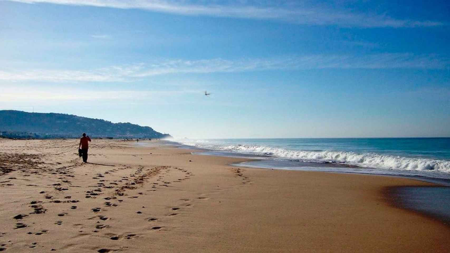 Una persona pasea por una playa desierta / EP