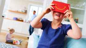 Una niña observa en 3D un juego de su móvil con las gafas de McDonald's