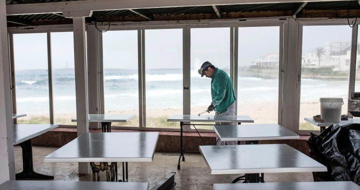 Un trabajador desinfecta las mesas de un restaurante de playa / EFE