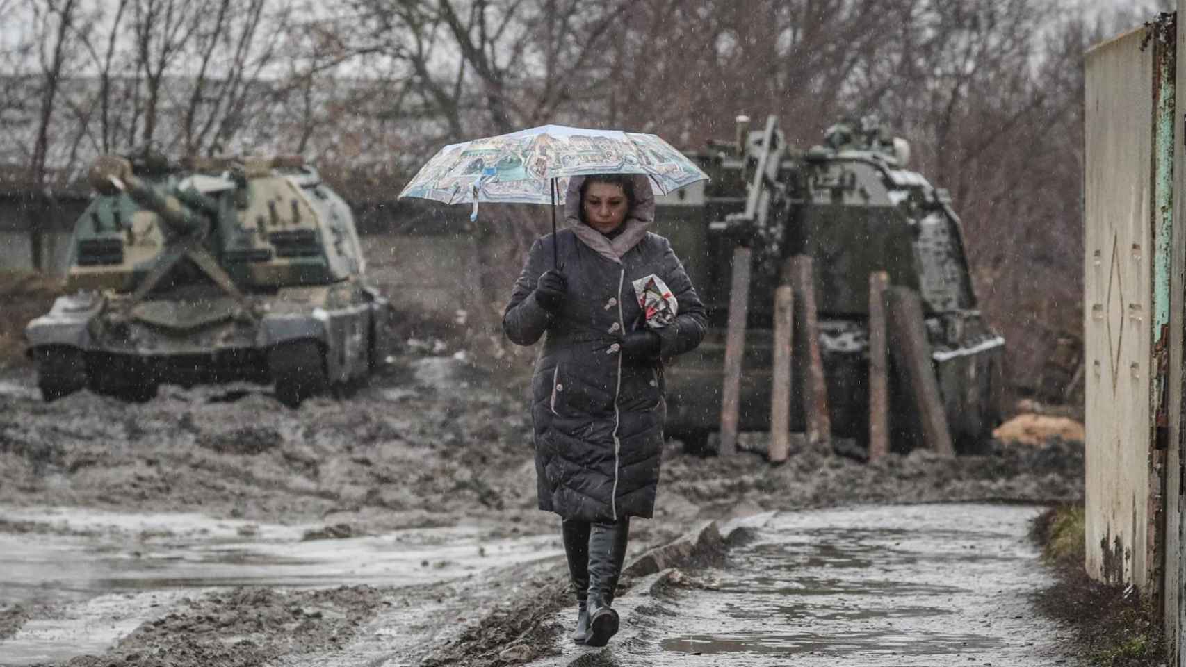 Una mujer camina cerca de vehículos armados en la estación de tren de la región de Rostov, Rusia / EFE
