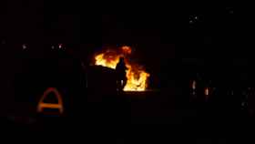 Un bombero apaga las llamas de un contenedor, como los que ardieron ayer en  / DAVID ZORRAKINO - EUROPA PRESS