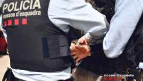 Dos agentes de los Mossos esposan a un detenido: un hombre ha sido arrestado por cultivar marihuana en El Pla / MOSSOS D'ESQUADRA