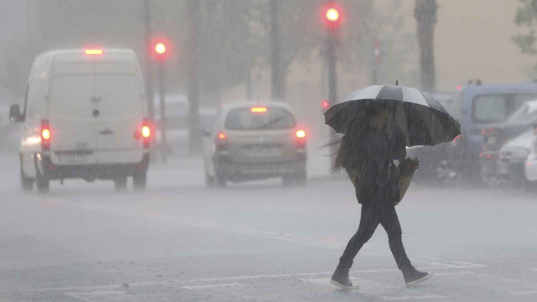Una persona cruza la calle en un día de lluvias en España. Previsión del tiempo / EFE