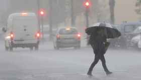 Una persona cruza la calle en un día de lluvias en España. Previsión del tiempo / EFE