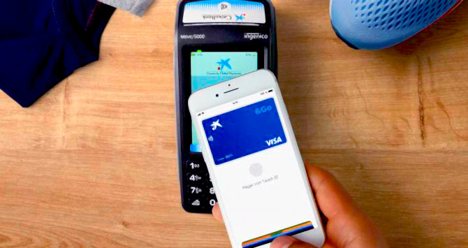 Un móvil con Apple Pay junto a un datáfono de Caixabank