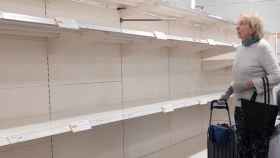 Una mujer busca productos que comprar en unas estanterías vacías de un supermercado en plena crisis del coronavirus / EP
