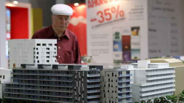 Un hombre contempla la maqueta de varios bloques de pisos / EFE